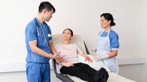 health care professionals treating a patient with a burn wound on hand
