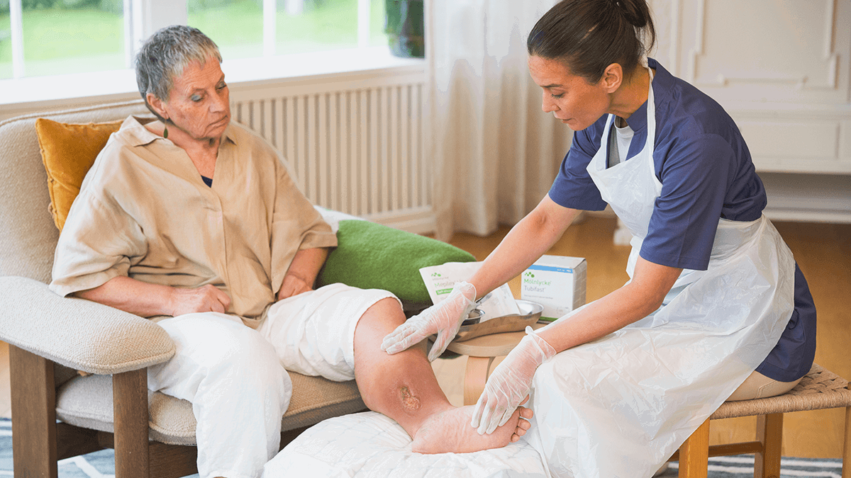A photo of a nurse inspecting the wound on the leg of a patient.