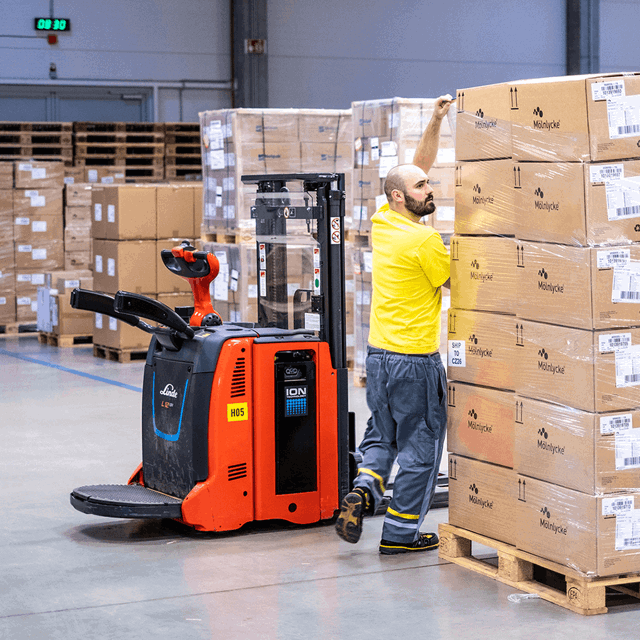 A photo of a warehouse worker applying cling film to a pallet.