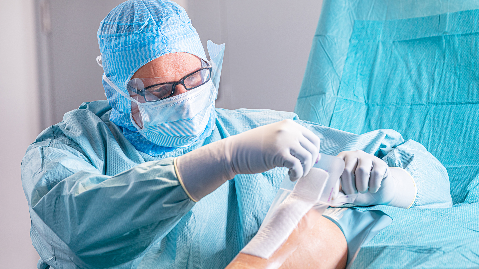 Un médecin vêtu d'une blouse chirurgicale applique un pansement sur une plaie pendant une opération
