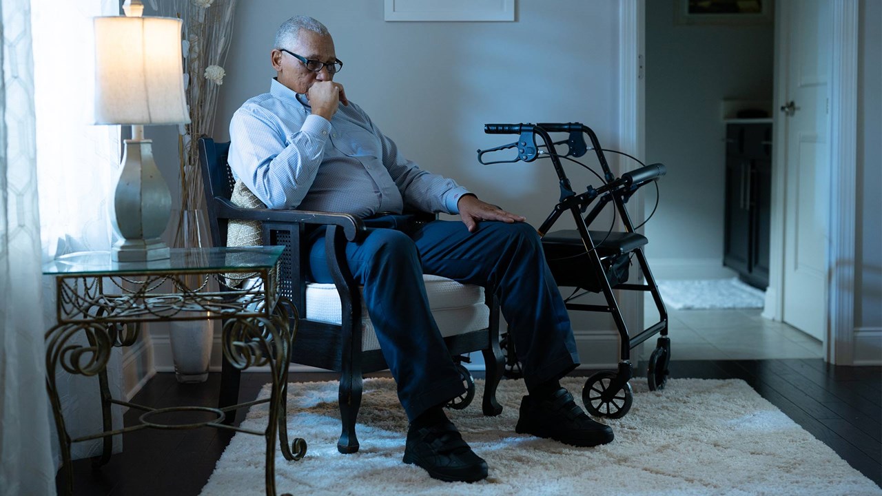 A photo of a man sitting in a chair alone. He looks depressed. 