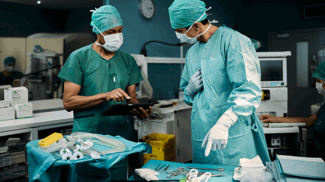 A photo of two surgeons discussing the contents of a surgical tray.