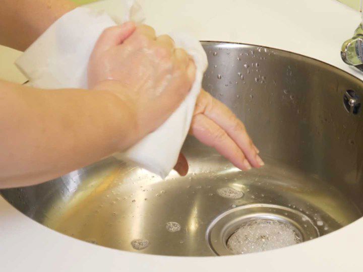 A photo of a two hands using a clean piece of cloth to dry off.
