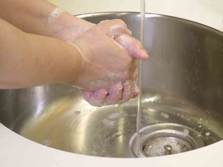 A photo of two hands washing with soap under running water. 