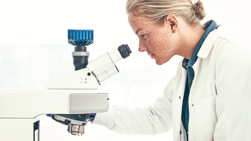 Laboratory professional examining a sample through a microscope