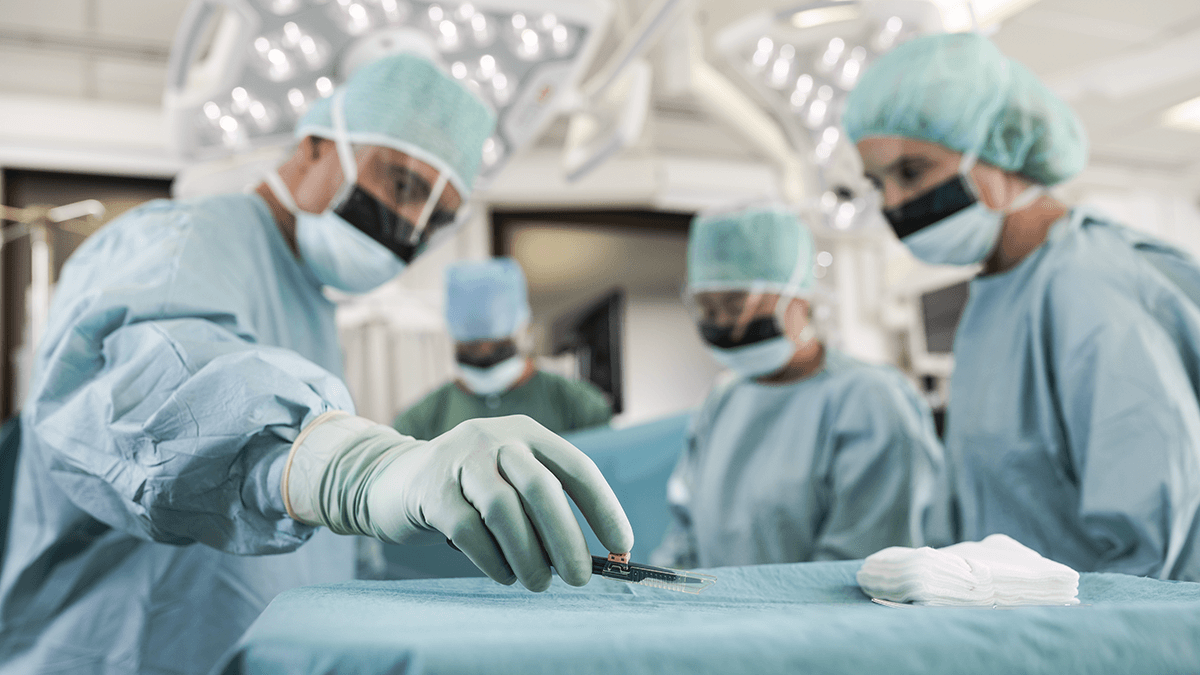 A photo of a scalpel being picked up by a surgeon. 