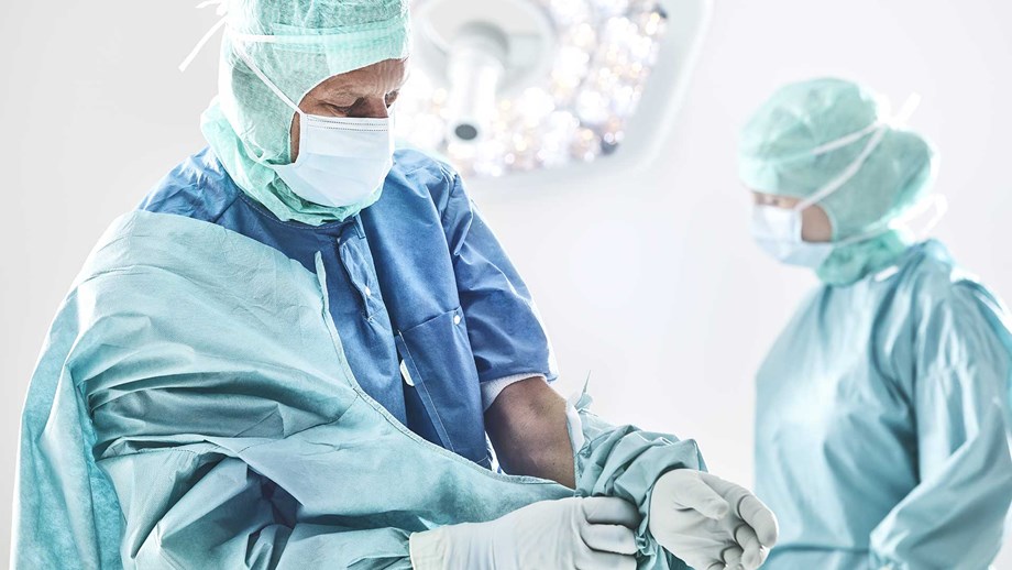 Surgeon donning a gown before surgery